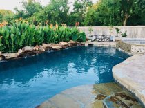 Freeform-lagoon-style-pool-with-raised-spa-paver-decking-and-pool-landscaping-
