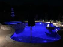 Freeform-pool-with-raised-spa-cocktail-table-and-LED-lights